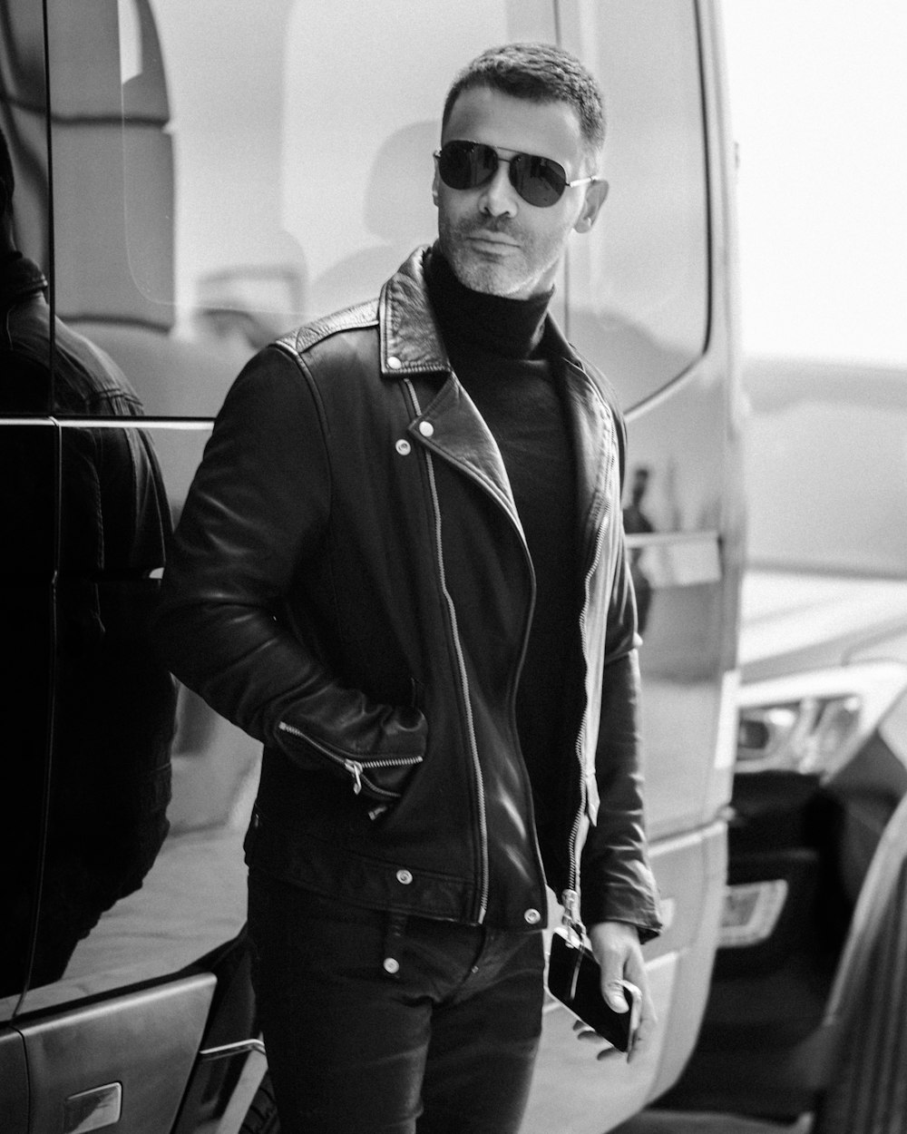 a man in a leather jacket standing next to a van