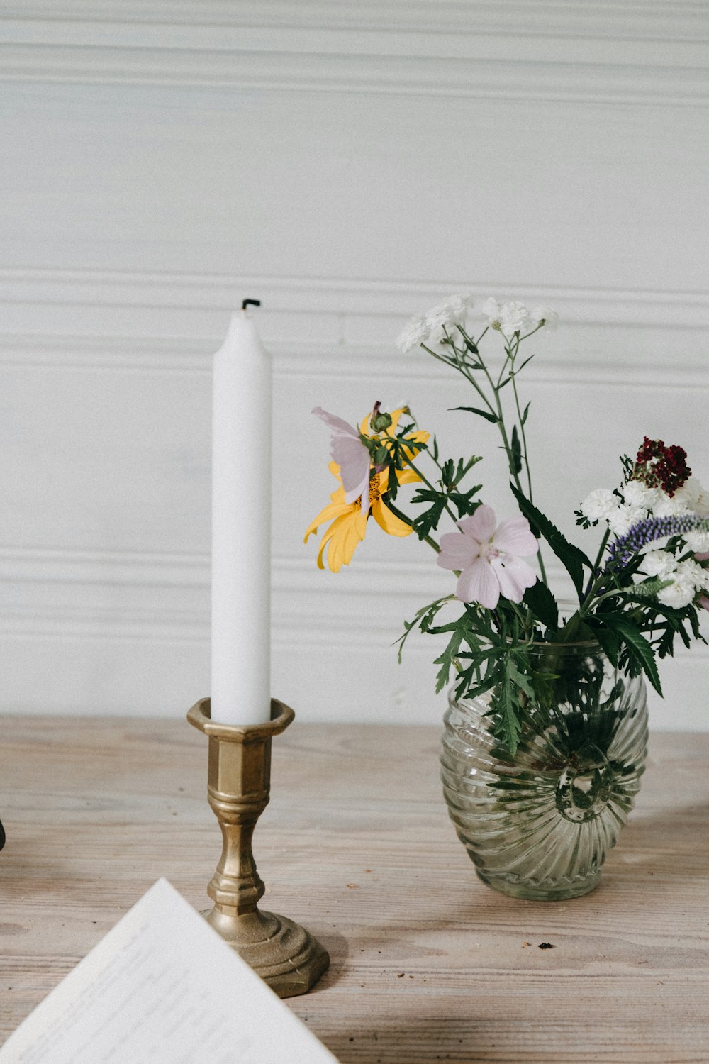 a vase with flowers and a candle on a table