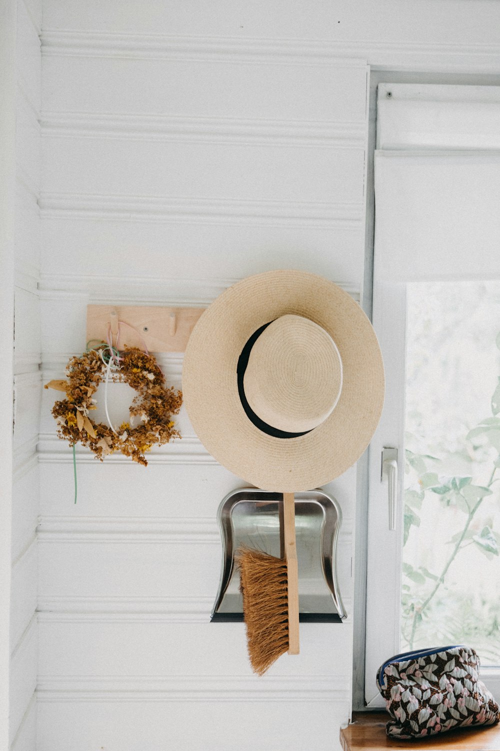 a hat, broom, and other items hanging on a wall