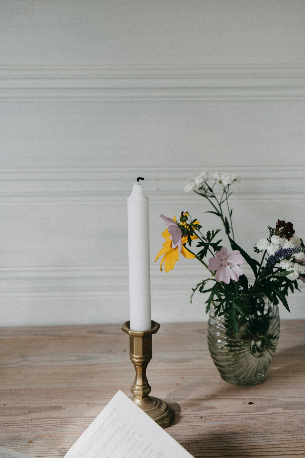 a white candle and some flowers on a table