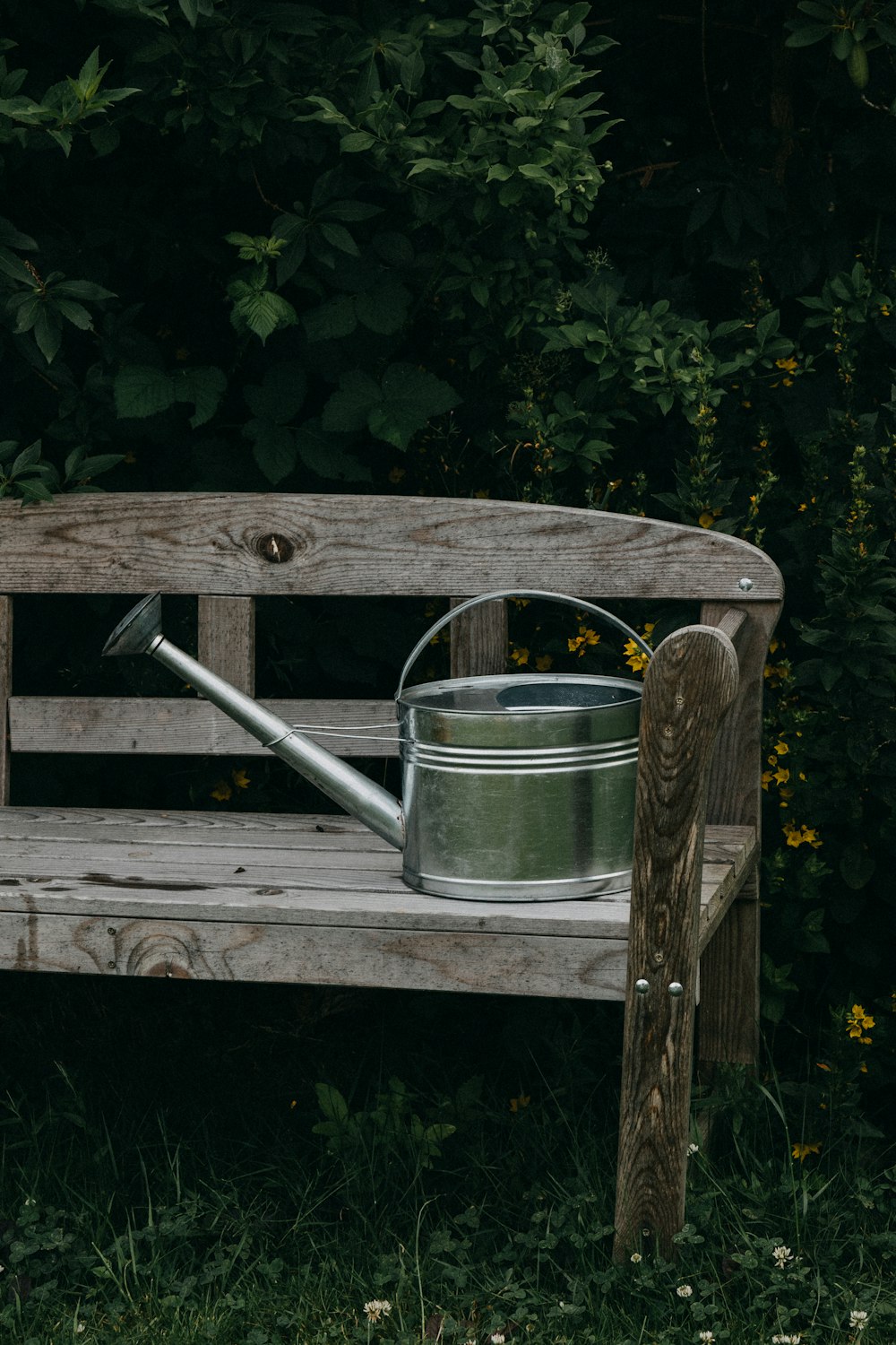 a wooden bench with a watering can on it
