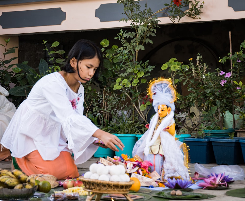 a woman in a white shirt is cutting a cake