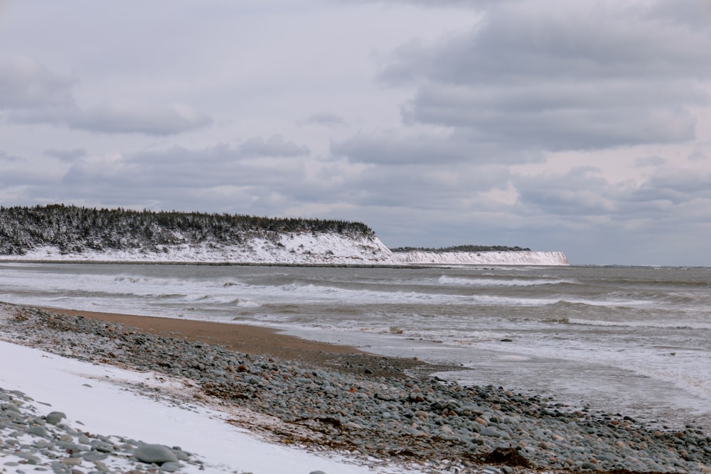 a snowy beach with a hill in the distance