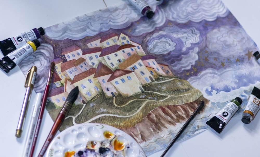 Una pintura de un pueblo con una paleta y pinceles
