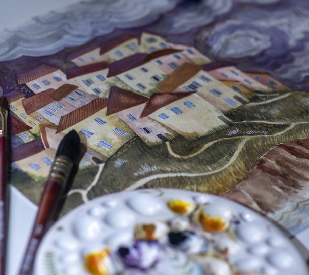 a table with a plate of food and paint brushes