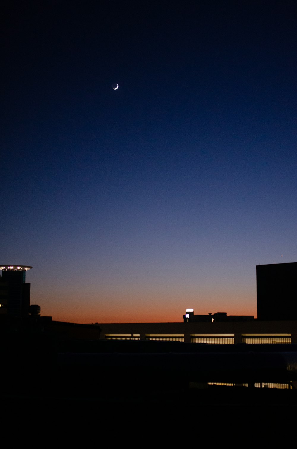 uma vista de uma cidade à noite com a lua no céu