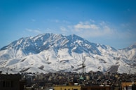 a snow covered mountain in the distance with buildings in the foreground