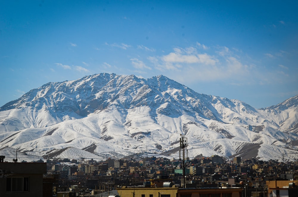 a snow covered mountain in the distance with buildings in the foreground