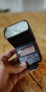 Close-up of a professional camera with a flash attachment on a wooden table.