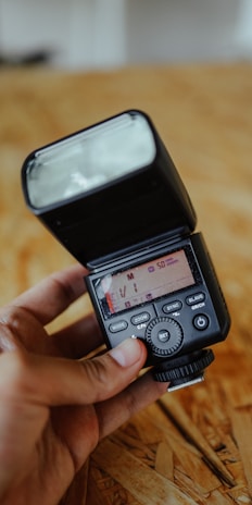Close-up of a professional camera with a flash attachment on a wooden table.