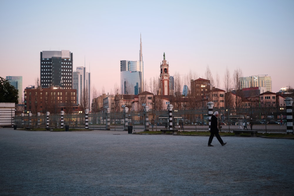 a man walking across a street next to tall buildings