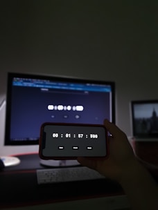 a person holding a cell phone in front of a computer