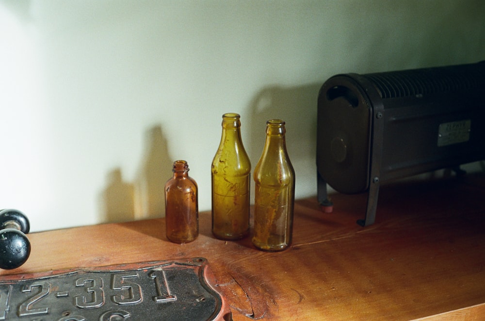 a wooden table topped with three brown bottles