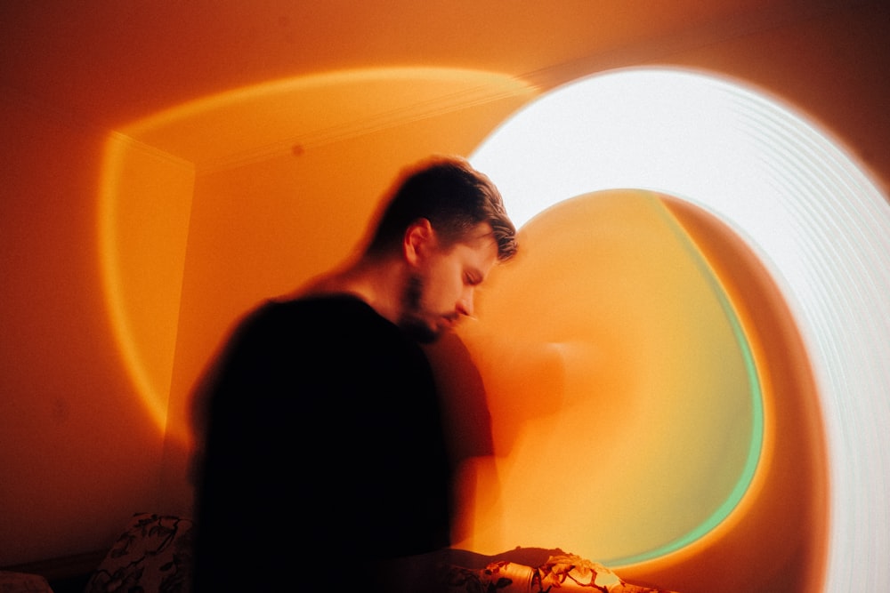 a man standing in a room with a pizza in front of him