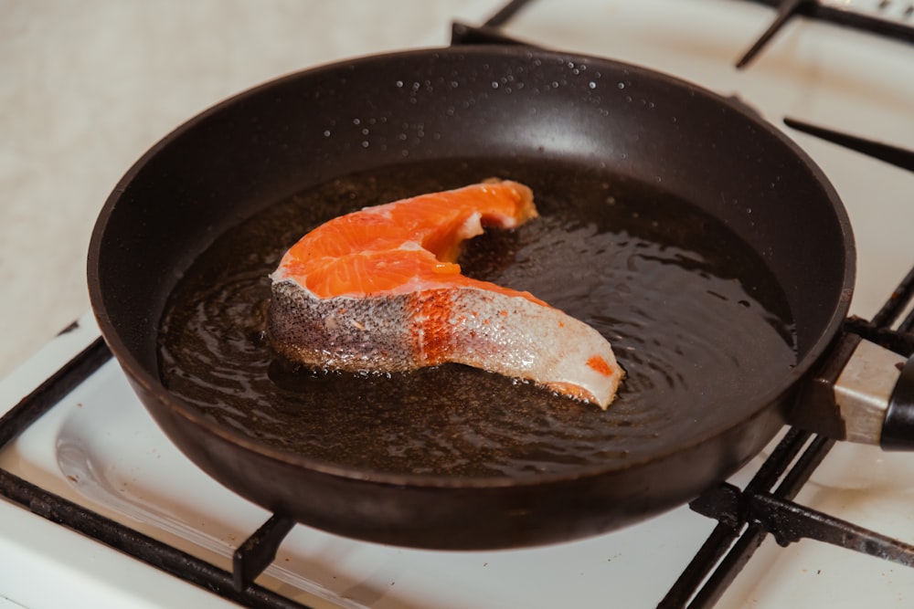 um peixe está sendo cozido em uma frigideira