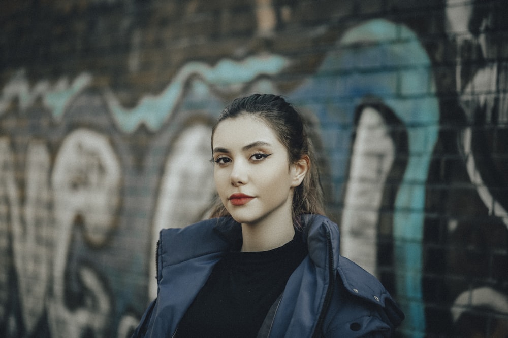 a woman standing in front of a graffiti covered wall