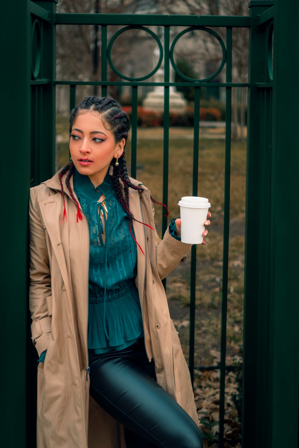 a woman in a trench coat holding a cup of coffee