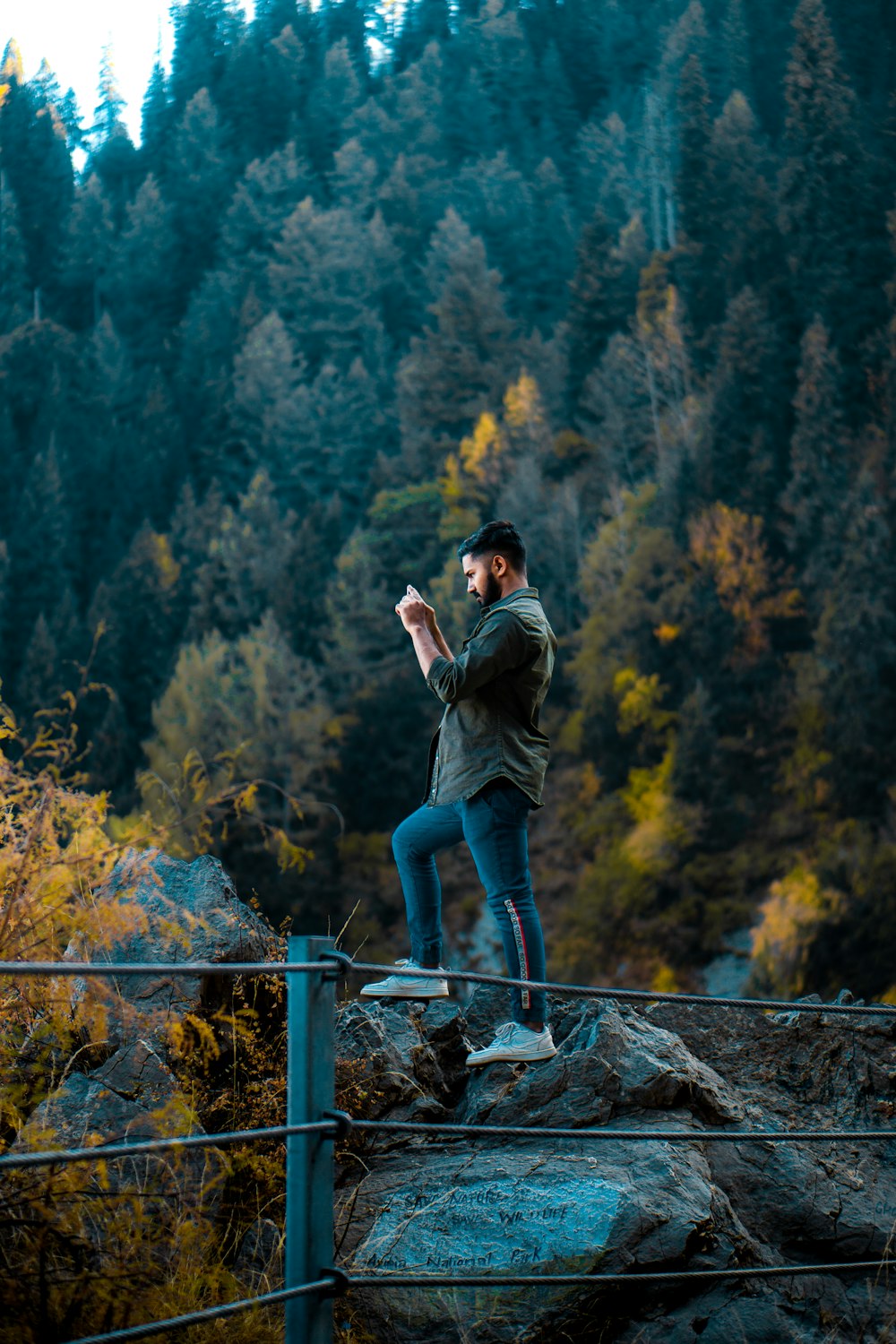 a man standing on top of a rock next to a forest