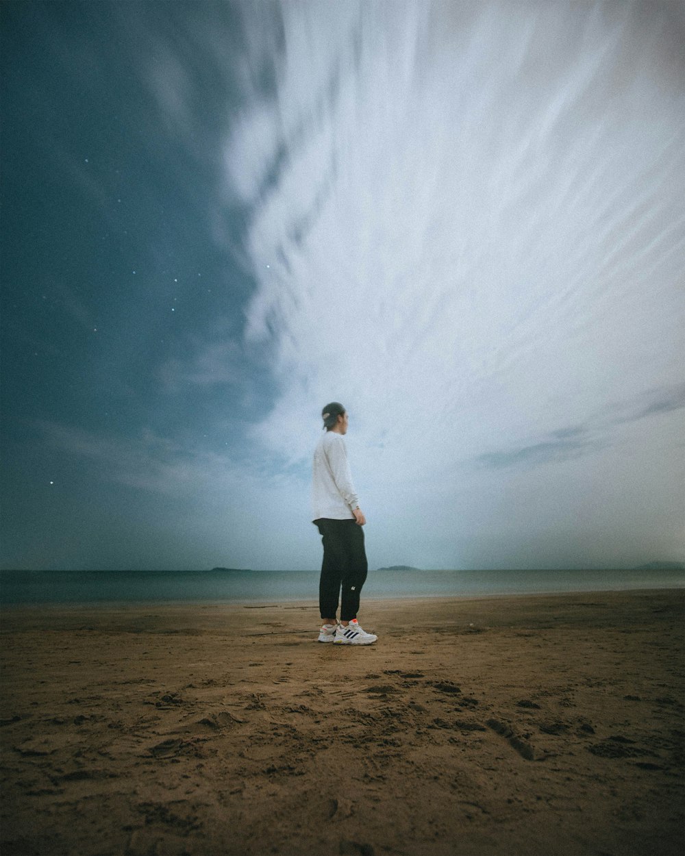 a man standing on top of a sandy beach under a cloudy sky