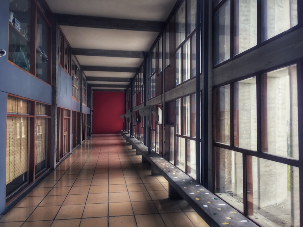 a long hallway with many windows and a bench