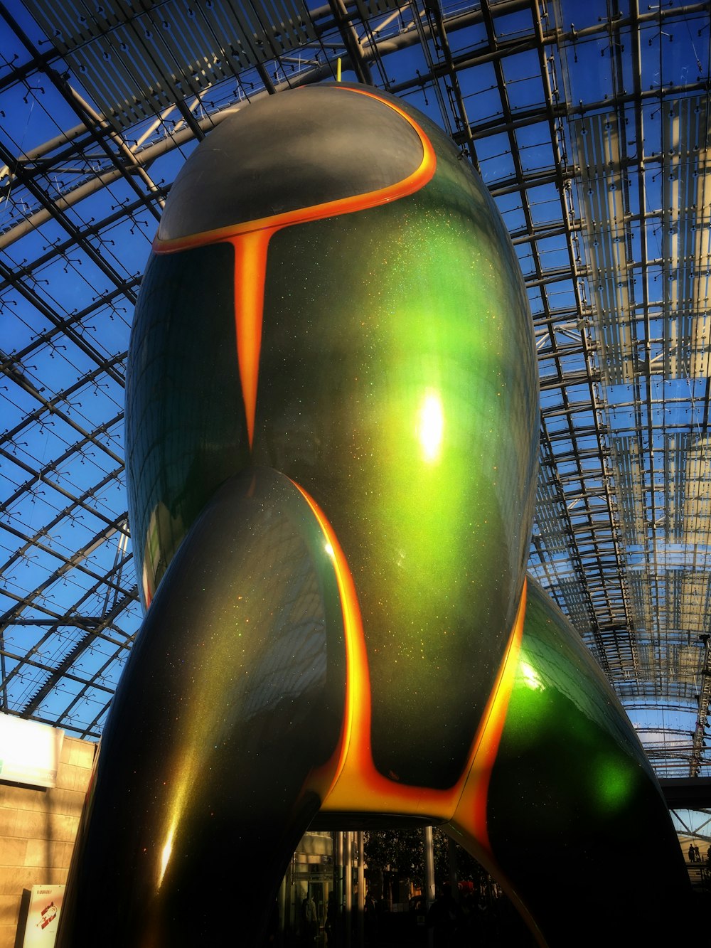 a large green and orange sculpture inside of a building