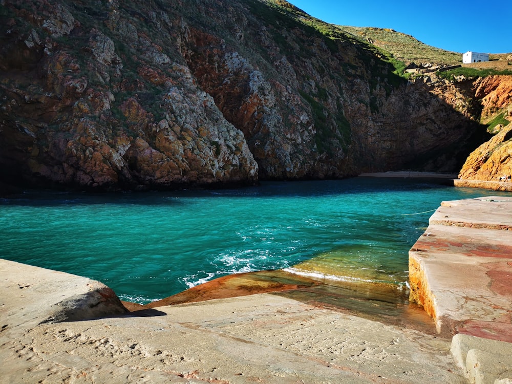 a body of water next to a rocky cliff