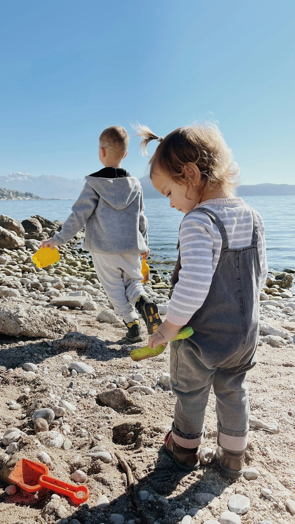 two young children playing with toys on the beach