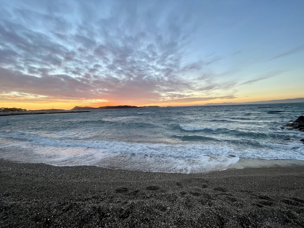 a beach with waves coming in to shore at sunset