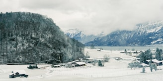 a snowy landscape with houses and mountains in the background