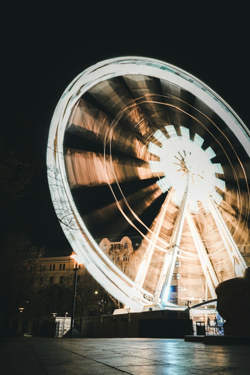 a ferris wheel at night with a building in the background