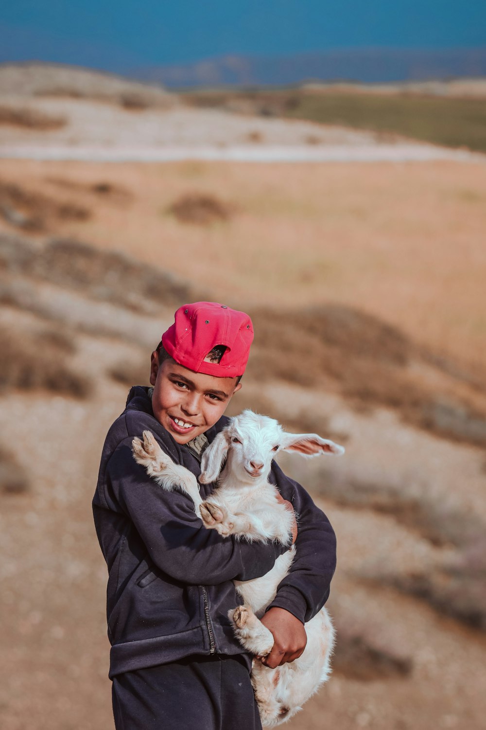 a young boy holding a baby goat in his arms