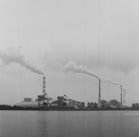 a black and white photo of smoke billowing from a factory