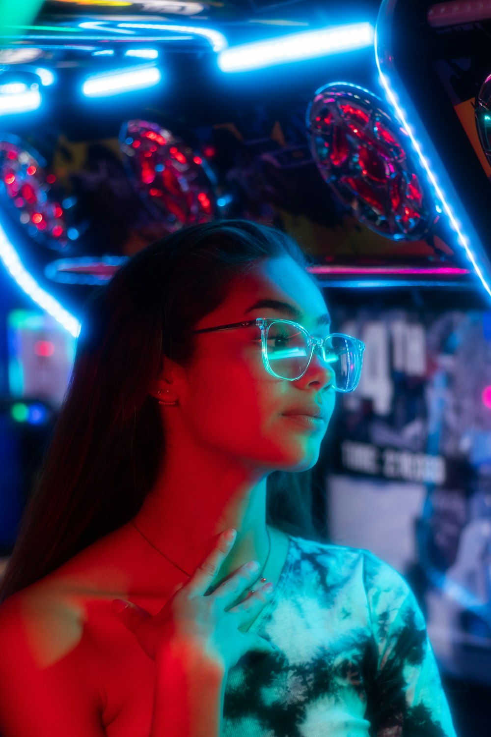 a woman wearing glasses standing in front of a neon sign
