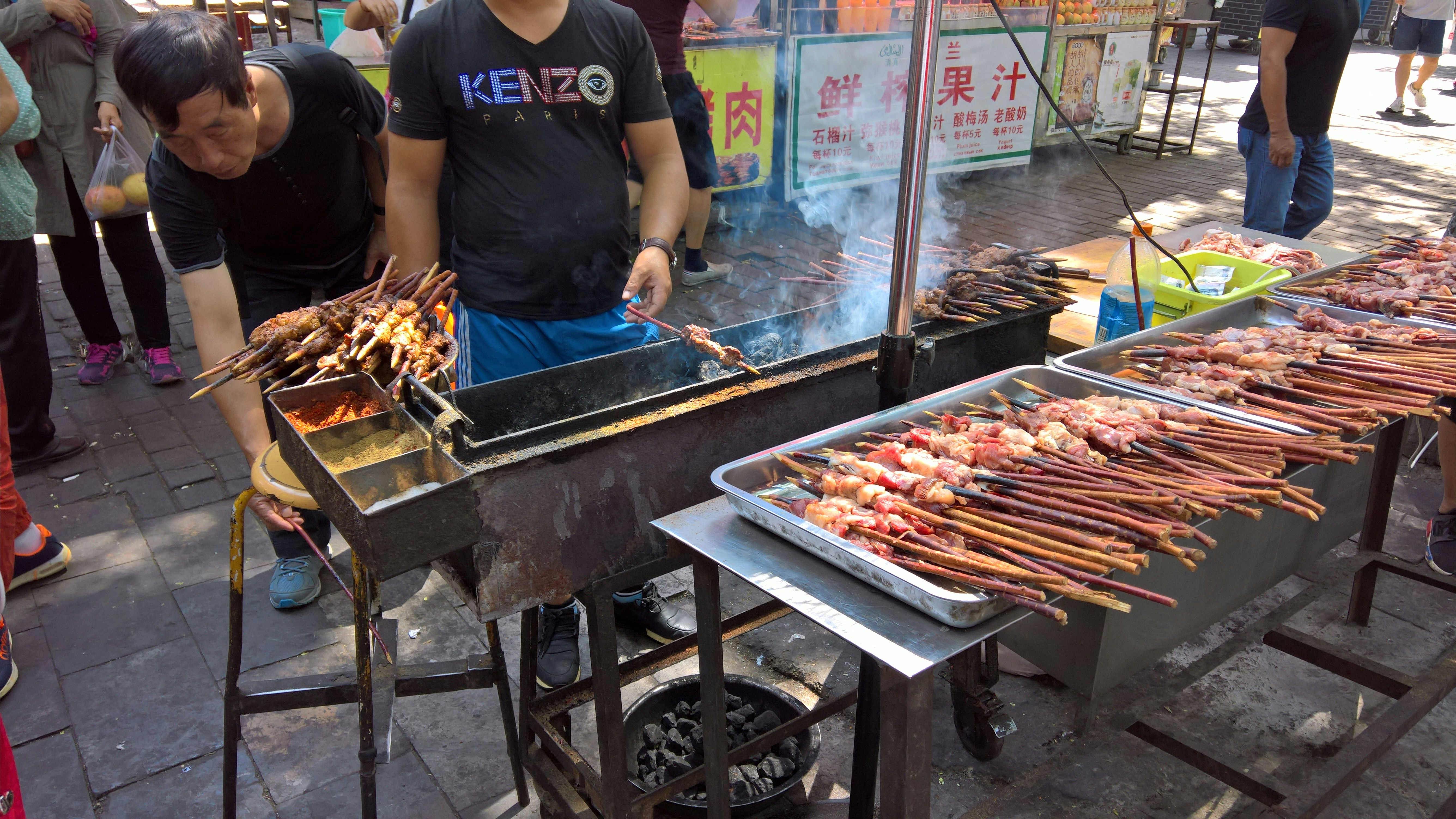 a man cooking food on a grill on a street