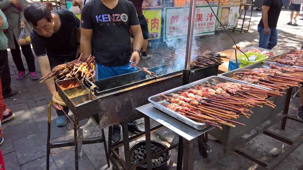a man cooking food on a grill on a street