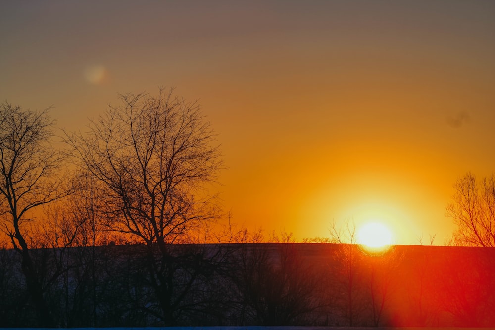 the sun is setting over a snowy field