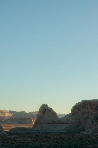 A serene landscape showing the three distinctive rocky formations of the Cuesta de Botucatu under a soft, earthy-toned sky.
