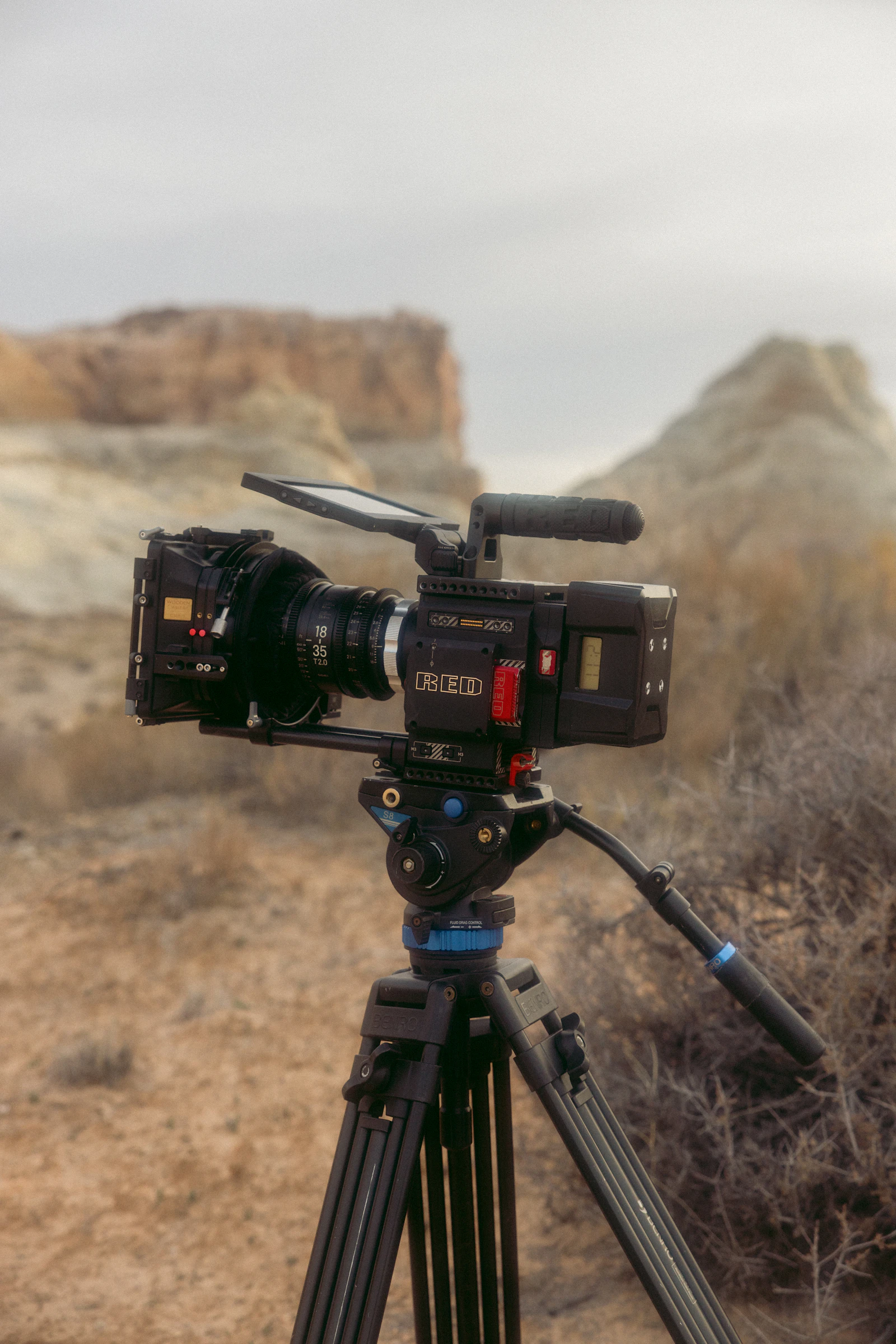 A video camera on a tripod in an open landscape.