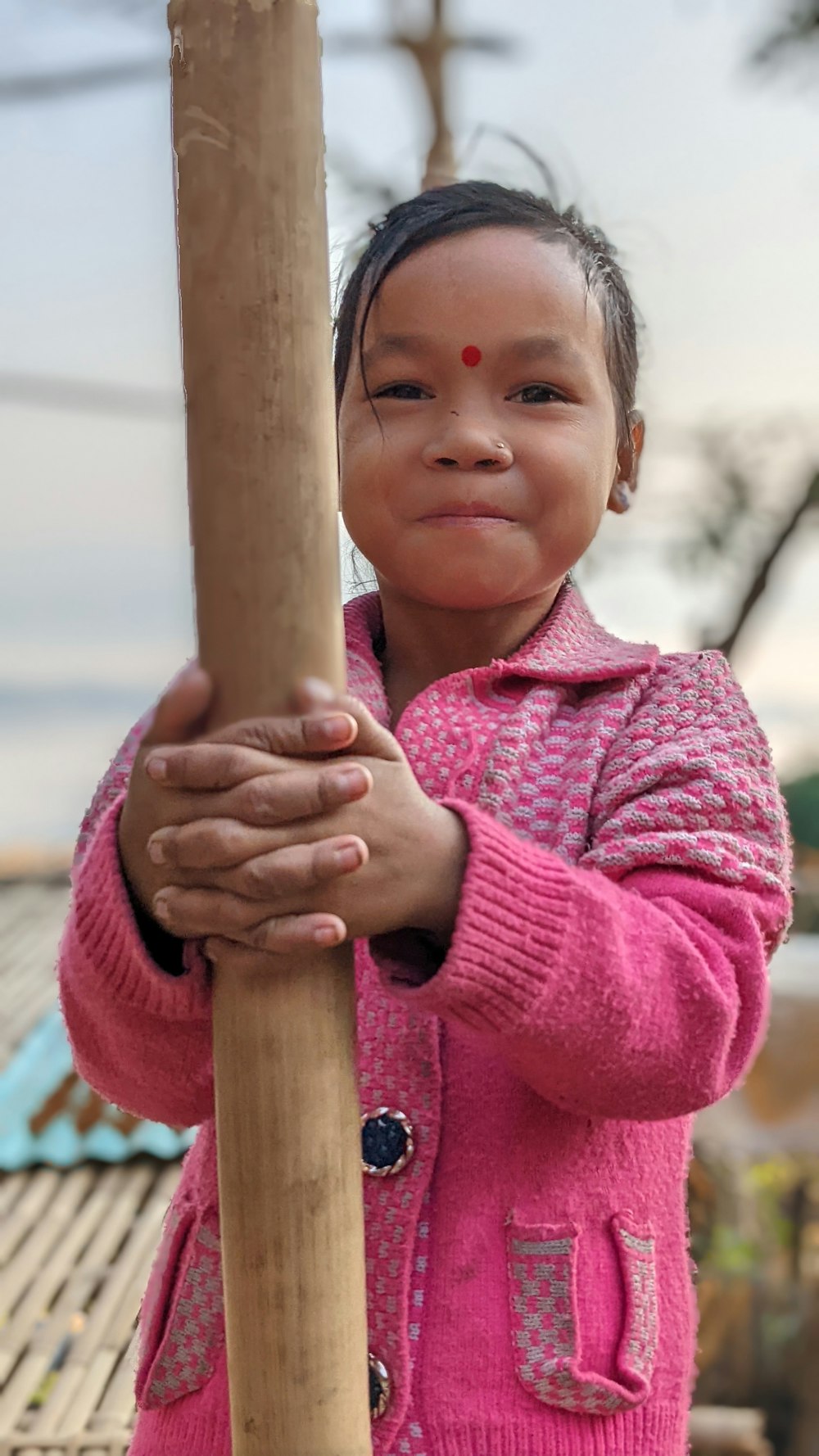 a young girl holding a wooden stick in her hands