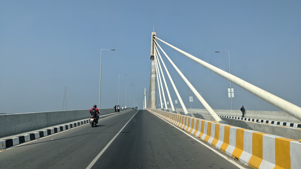 a man riding a motorcycle across a bridge