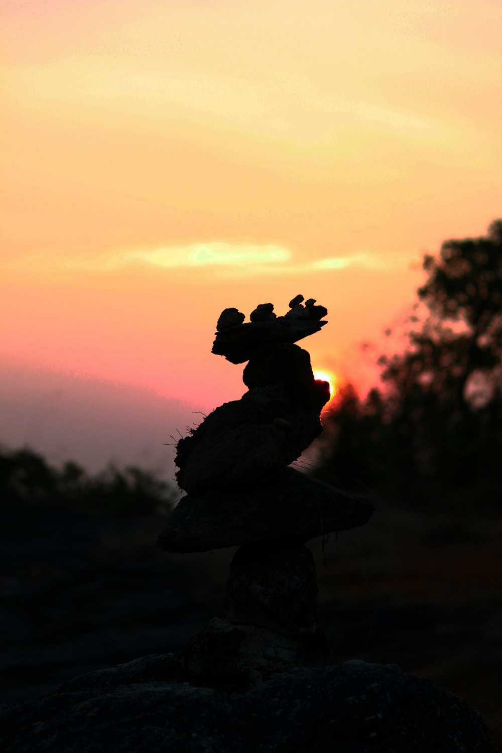 a stack of rocks with a sunset in the background
