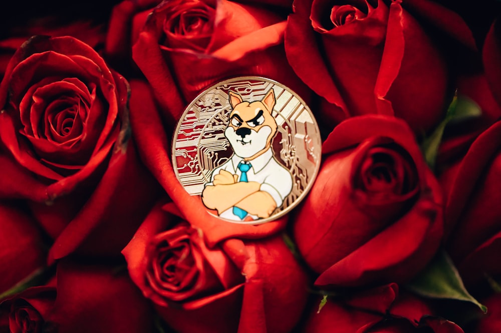 a pin with a cartoon character on it surrounded by red roses