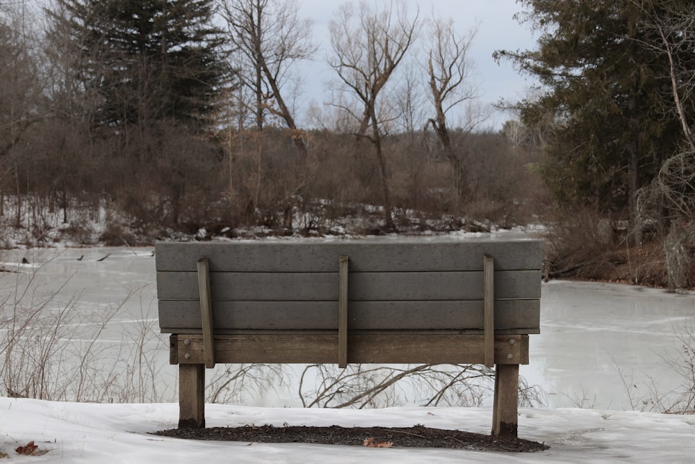 a wooden bench sitting on top of a snow covered field