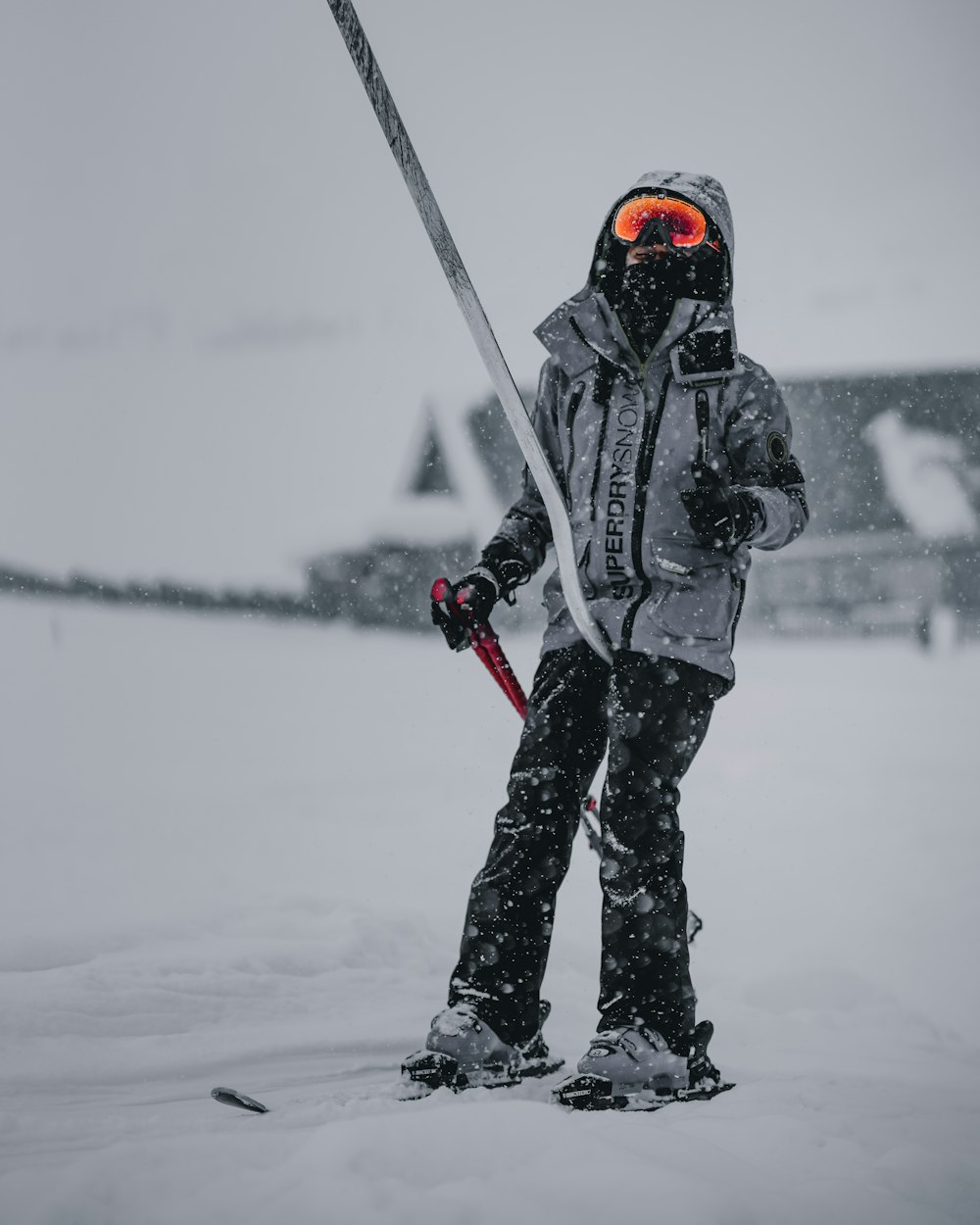 a person standing in the snow holding a pair of skis