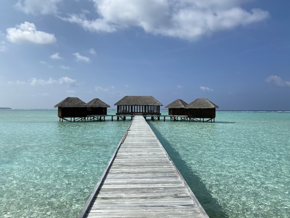 a wooden dock leading to a pier with huts in the water