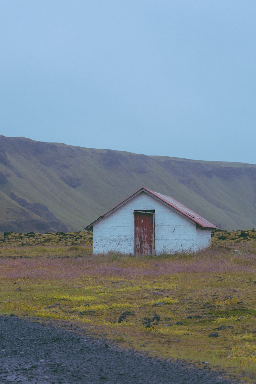 a small white building sitting in the middle of a field