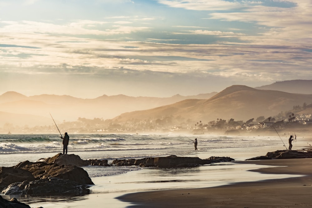 a couple of people standing on top of a beach next to the ocean