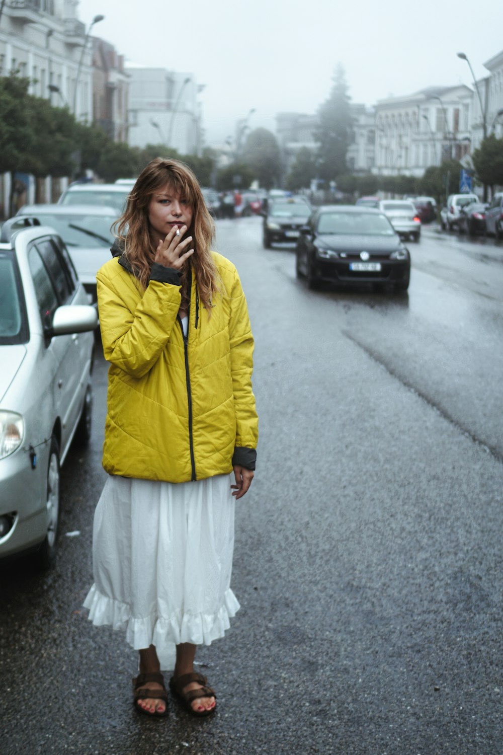 a woman standing in the middle of a street talking on a cell phone