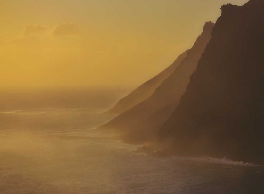 El sol se está poniendo sobre las montañas y el océano