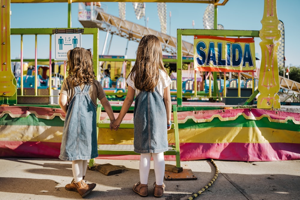 two little girls standing in front of a carnival ride